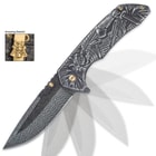 The knife is shown in action with its assisted opening mechanism, flipper and gold pocket clip with skull medallion.