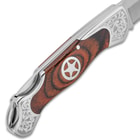 Detailed view of the knife’s wooden handle scaled with silver star medallion and decorative etching.
