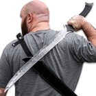 Person wearing shoulder harness scabbard with sword drawn.