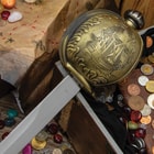 The basket hilt guard with pirate ship sailing on the ocean artwork lays atop an open treasure chest with map. 