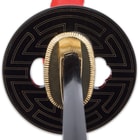 The hardwood handle is wrapped in faux rayskin and red cord and has an intricately detailed metal alloy tsuba