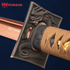 Close view of sea dragon embossed on square copper tsuba with peakings of the copper finish blade and shinwa emblem
