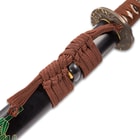 The scabbard has a braided brown hanging cord wrapped around it. 