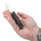 The mini OTF knife shown in hand
