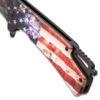 Upclose view of the patrotic pocket knife handle displaying a distressed american flag with a black glass breaking pommel on the end.
