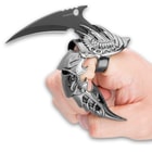 Claw knife is shown with finger bent inside the finger guard with blade sticking out. 