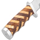 A top view of the walnut and olive wood handle in basket-weave pattern and stainless steel pommel.