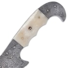 The curved Damascus steel handle has cream-colored bone handle scales, accented with mosaic rosettes and brass pins
