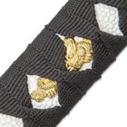 An ornate gold color design can be seen peeking out from the black cord wrapping the handle of the Samurai sword. 