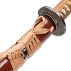 Detailed look at the speckled wine-red hardwood scabbard with brown hanging cord. 