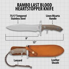 Non-reflective "Rambo" knife being held in front of leather sheath on a back ground of wood and shell casings. 
