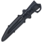 Black "Undercover" stinger knife being held through the open ring pommel in front of black knife sheath attached to utility jacket. 
