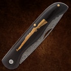 Closed folding knife with rifle inlay on dark handle