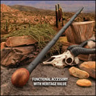 Walking stick with wooden handle, skull, and rocks in desert setting