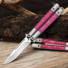 Butterfly knife with pink handles on a wooden surface