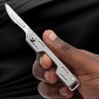 Hand holding a silver folding knife with open blade