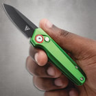 Hand holding a green folding knife with black blade