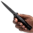 Hand holding a black stiletto knife with a sharp blade