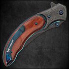 Upclose view of the pocket knife's "raindrop" pattern blade with metallic blue thumbstuds and the inscription "shinwa." 
