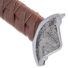 Zoomed view of viking designed pommel with glimpse of brown leather wrapped handle
