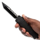 Hand holding a black tactical knife