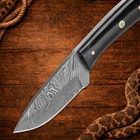 Knife blade with Damascus pattern on wood surface