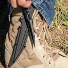 Slim black knife with pentrating point protected inside black nylon sheath while the handle and open-ring pommel remains exposed.
