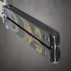 Close-up of butterfly knife handle with dragon artwork
