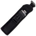 Closed switchblade enclosed in black nylon belt sheath with open buckle closure. 
