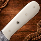 Close-up of white knife handle with decorative pin