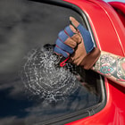 Gloved hand using knife to break car window glass