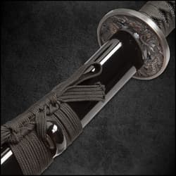 Close shot of katana handle with genuine rayskin wrapped in black cord showcasing brass menuki and wooden mekugi