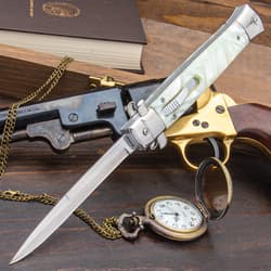 Pearl handle stiletto pock knife with silver accents displayed on a variety of antique items.