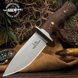 9 5/8" stainless steel fixed blade knife with G10 curved handle and brass pins on a background of moss, greenery, wood, and seude.