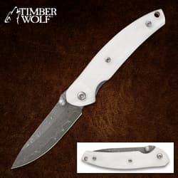 White-handled folding knife with Damascus blade on brown background