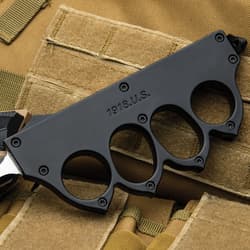 Close-up of black knuckle grip knife on tactical vest