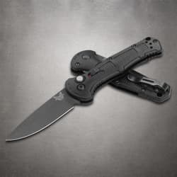 Partially open black folding knife with clip on gray surface