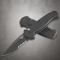 Two black folding knives crossed on gray surface
