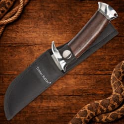 Knife in black sheath with wooden handle on wooden background