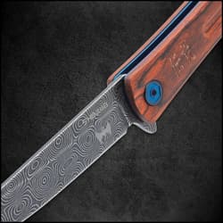 Extended slim pocket-knife displayed upright at an angle with a bloodwood handle, metallic blue accents, and a grey upswept blade with a raised raindrop pattern on a white background.