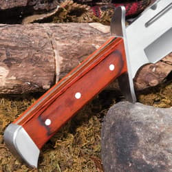 Upclose view of a polished pakkawood handle with silver accents on a background of wood, moss, and rock.