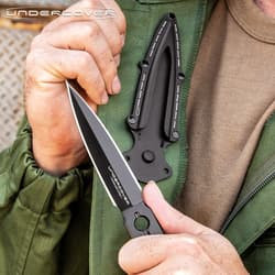 Person holding black dagger near green jacket
