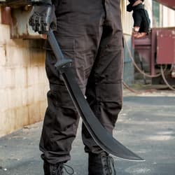 A person dressed in tactical gear is shown holding the sword with curved hard coated blade.