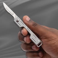 Hand holding a Tanso scalpel knife against a gray background
