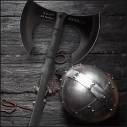 Black axe and metal helmet on wooden surface