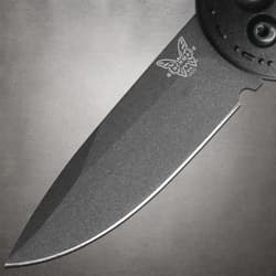 Close-up of black knife blade with logo on gray background