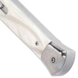 Upclose angled view of the end of a pearl handle switchblade with mirror polished silver accents.