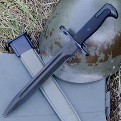 Bayonet and scabbard on grass with a helmet