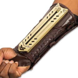 Retracted tactical gauntlet compossed of mahogany brown faux leather and gold blade enclosure attached to the inner forearm.