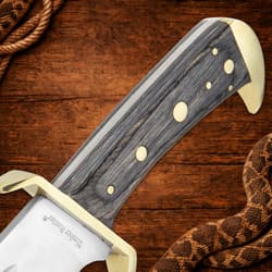 Side view of the gray hardwood handle with brass-plated guard and angled brass-plated pommel.